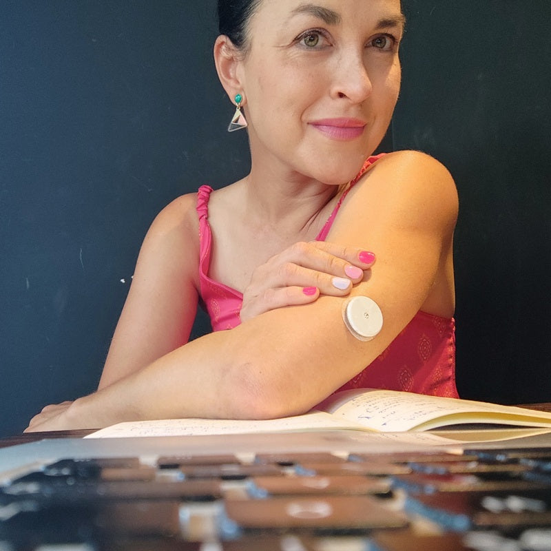 A woman with the Abbott glucose sensor applied to her left arm