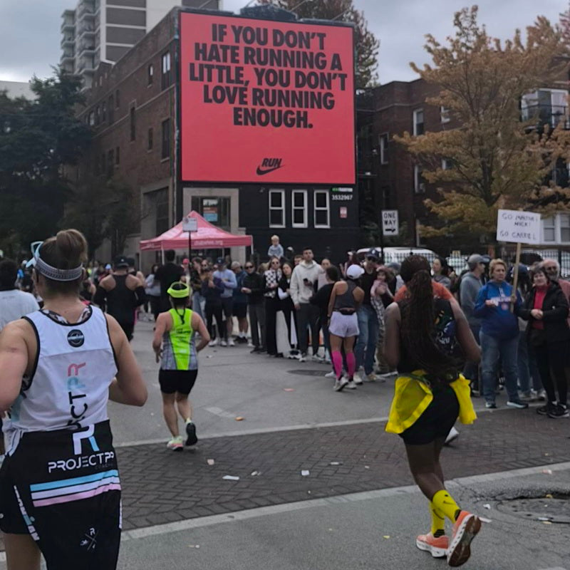 Runners are seen during the Chicago Marathon passing in front of a large Nike advertisement with a motivational message.