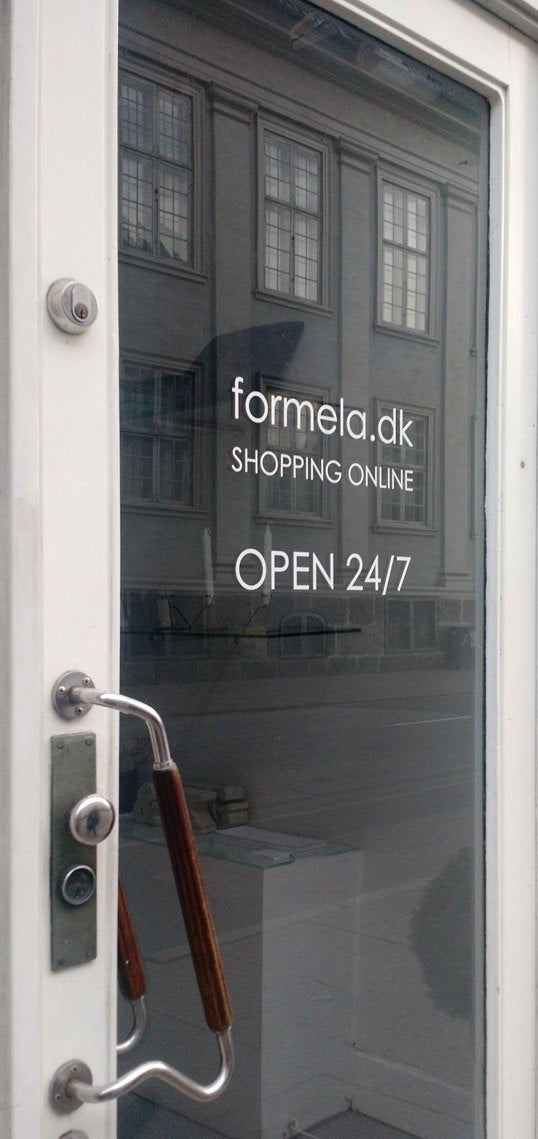 Photograph of a store's entrance door with the brand name Formela visible on the glass