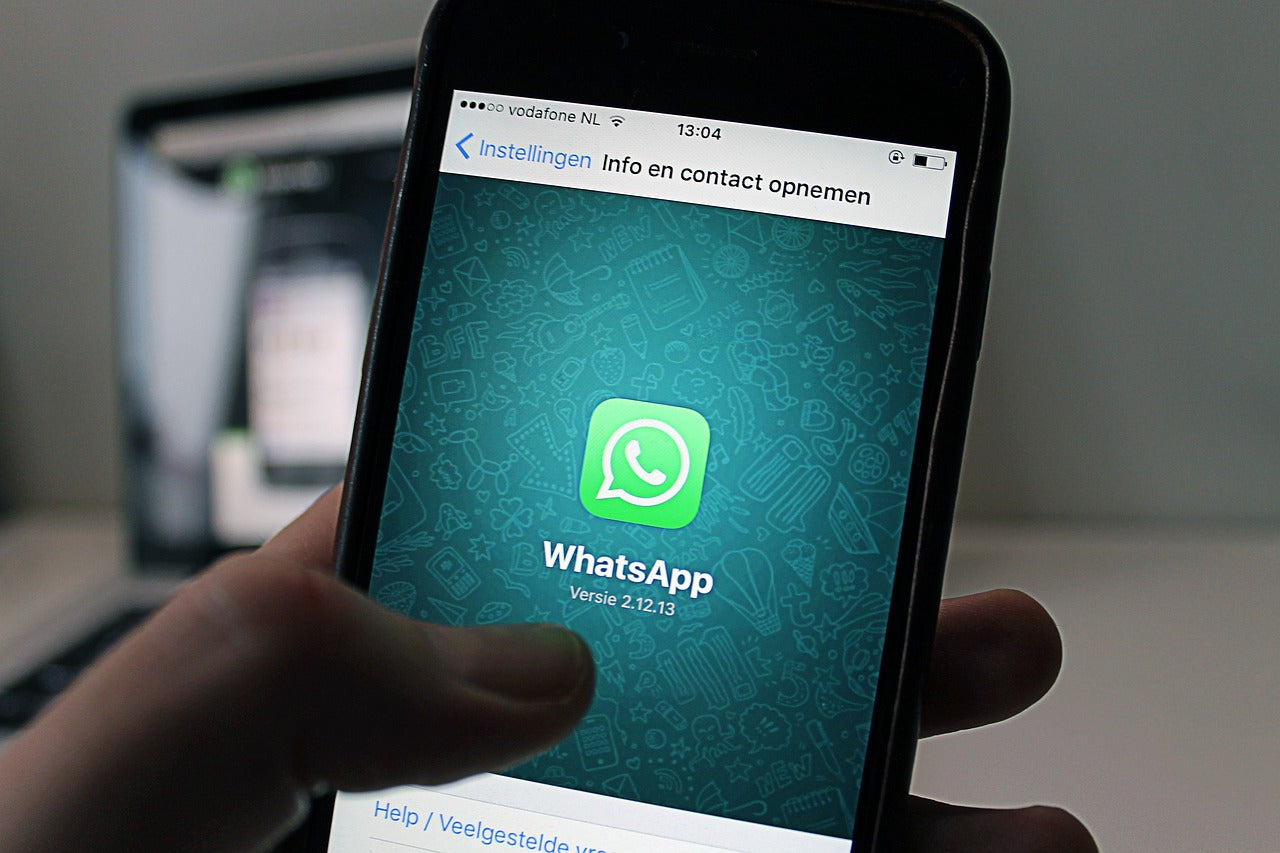 A hand holding a smartphone with the WhatsApp application displayed on its screen.