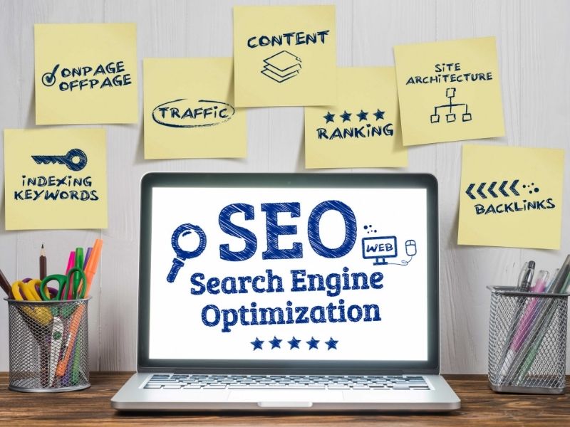 Personal computer showing SEO objectives on its screen and sticky notes around it with SEO tasks.