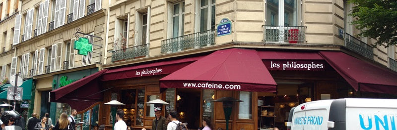 Facade of a classic building with brown awnings that say cafeine.com
