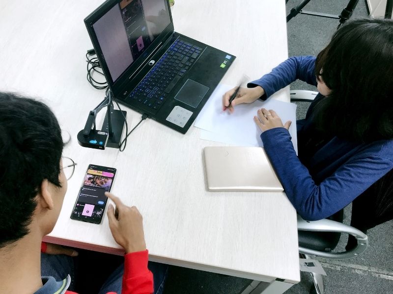 Man and woman conducting a usability test on a laptop and a smartphone.